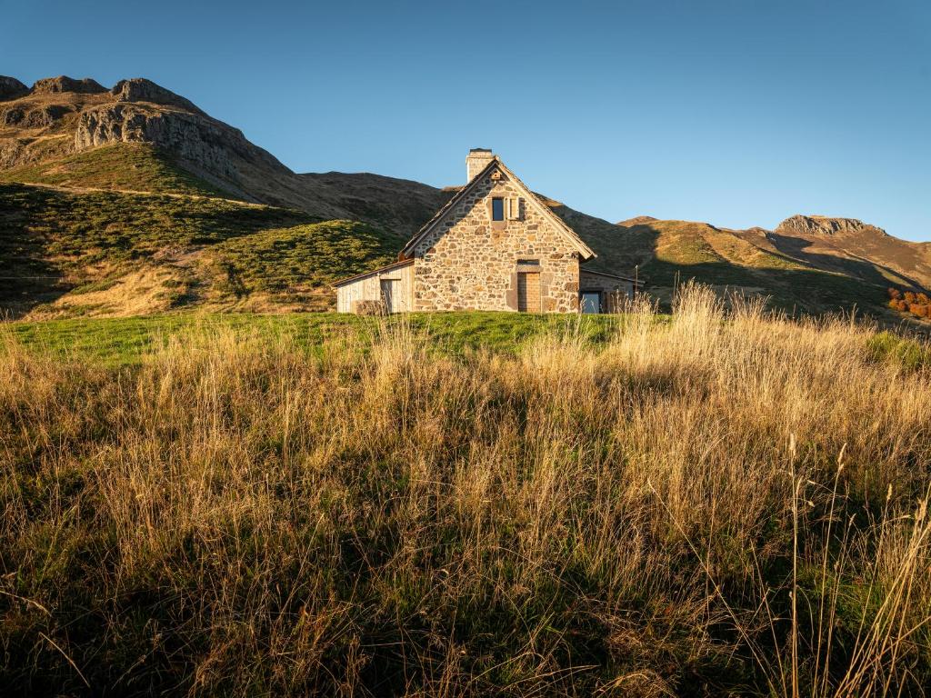 an old stone house in a field of grass at Buron du Tournel, un écrin d'exception in Le Lioran