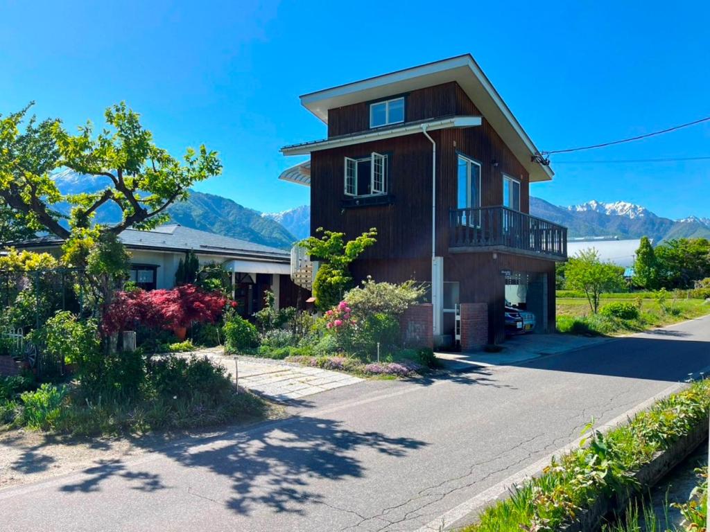 a house on a street with mountains in the background at コテージ野の香 in Omachi