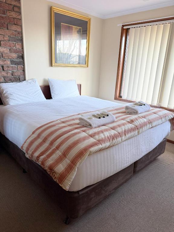 a large bed in a bedroom with a large window at Speers Point Serviced Apartments in Cockle Creek