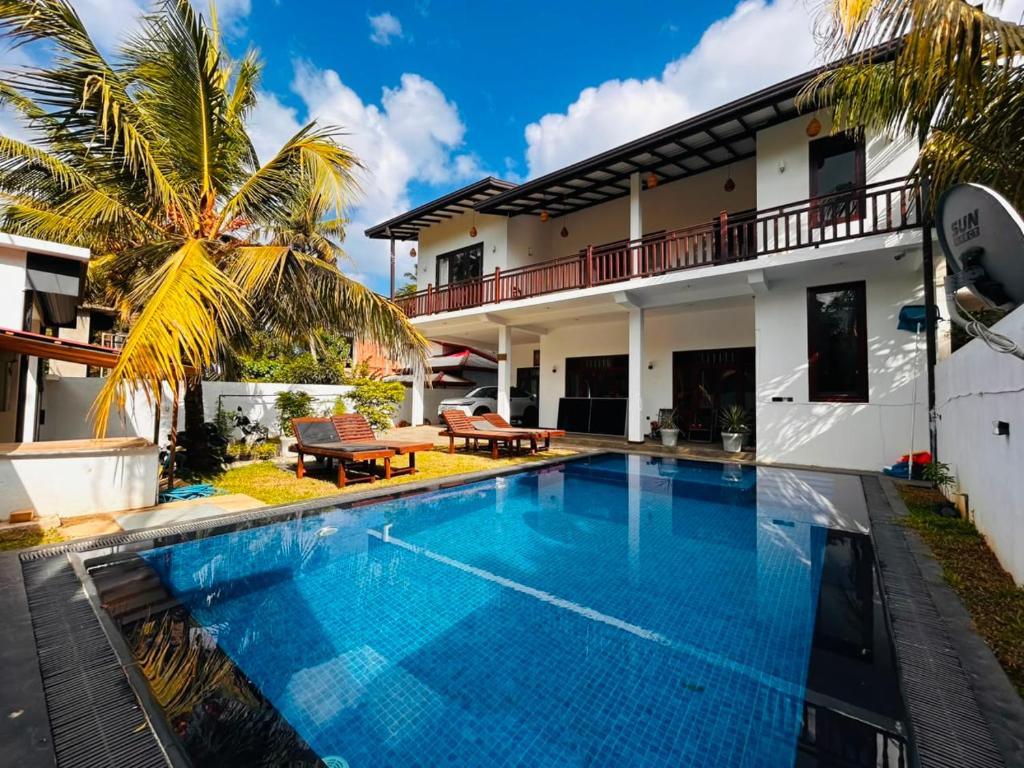 a villa with a swimming pool in front of a house at Parrot Perch Villa Dickwella in Dickwella