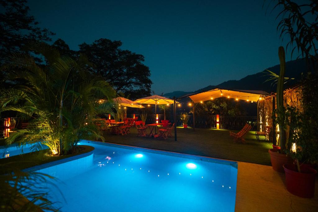a swimming pool at night with tables and umbrellas at Hostal Doña Emma in Pahuatlán del Valle