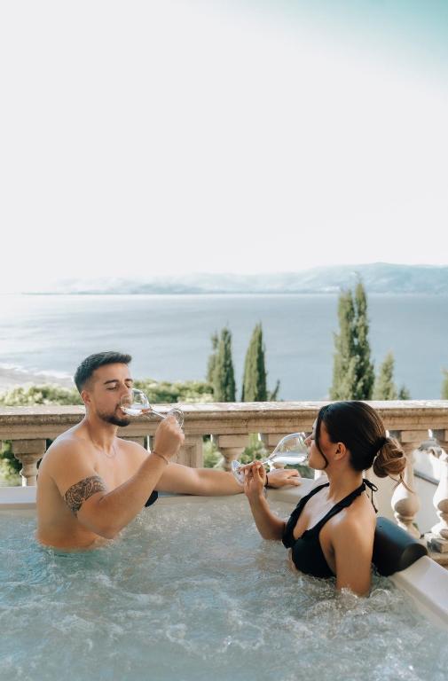 a man and a woman sitting in a swimming pool at Garden Palace Hotel in Castiglione del Lago
