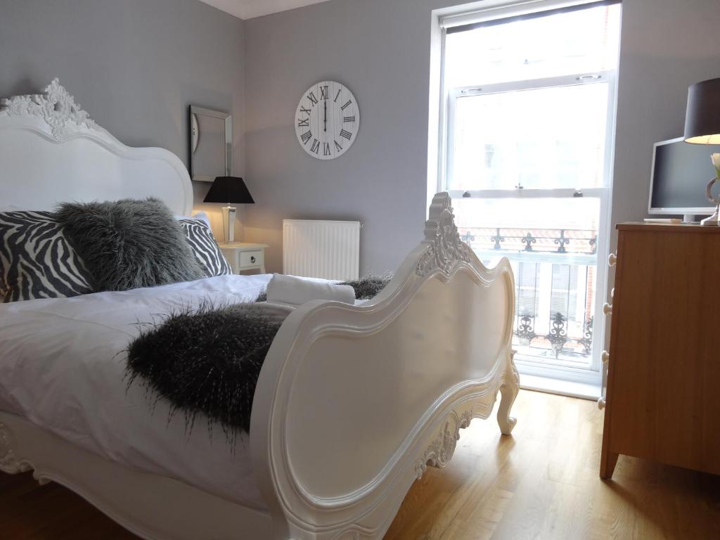 a bedroom with a white bed and a clock on the wall at Burlington Beach Apartments in Brighton & Hove