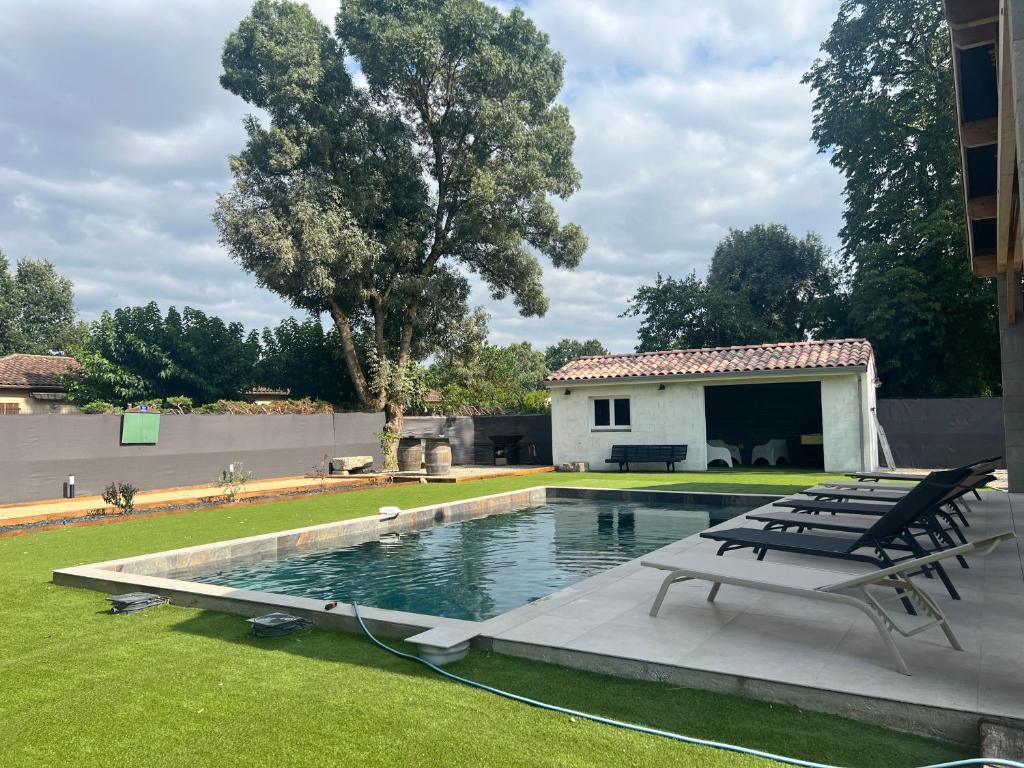 a pool with two lounge chairs and a house at Gîte du Grand Frêne in Nérac