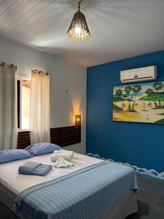 a bedroom with a bed with a blue wall at Casa Cochilo na Rede in Beberibe
