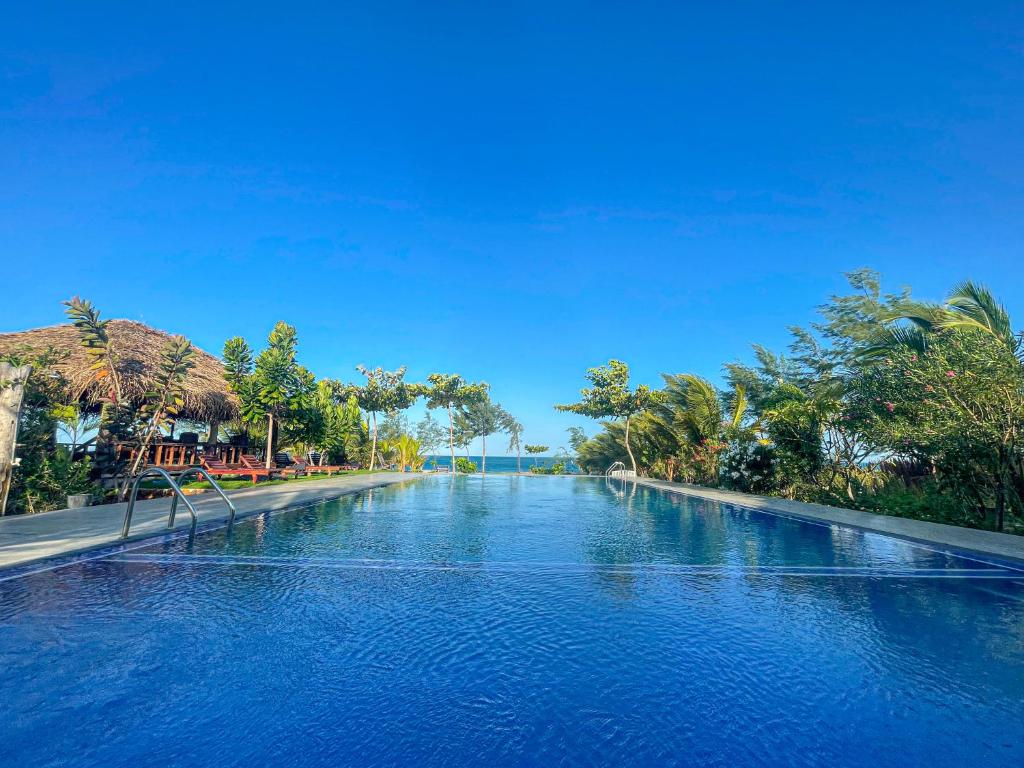 a large swimming pool with blue water and trees at Whisky Point Surf Cabanas in Ampara