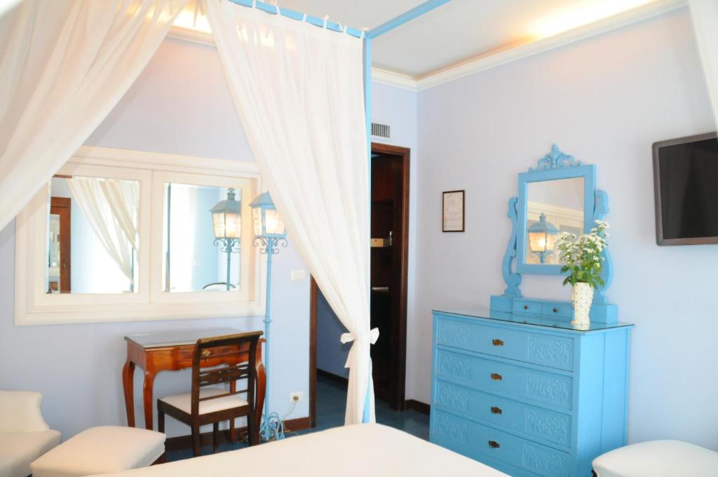 a bedroom with a blue dresser and a window at Hotel Palladio in Giardini Naxos