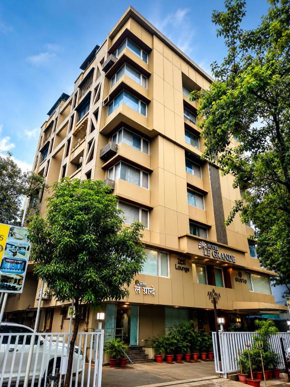a tall building with trees in front of it at Hotel Le Grande - Mumbai International Airport in Mumbai