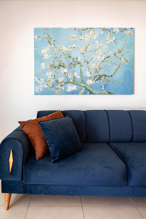 a blue couch in a room with a painting on the wall at 3 Bedroom Apartment, Easy Parking in Alexandroupoli