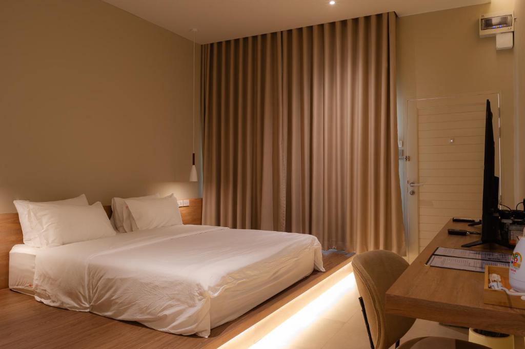 a bedroom with a white bed and a desk and a desk at The Cozy Hotel in Phetchaburi