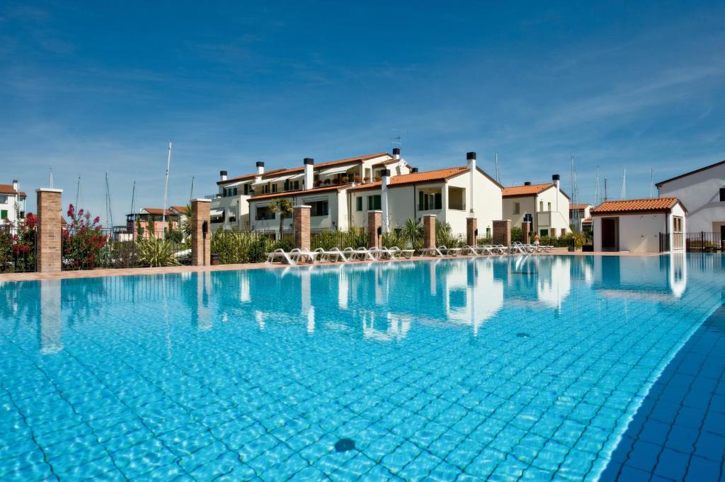 a large blue swimming pool with houses in the background at Residence Maestrale in Caorle