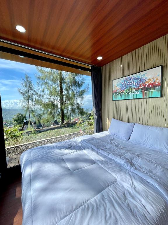 a large bed in a room with a large window at Kayana Capsul Dieng in Kejajar