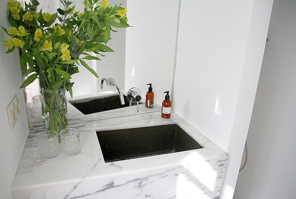 a bathroom sink with a vase of flowers and a mirror at Senhora do Cabo Meco Homy Holidays in Sesimbra