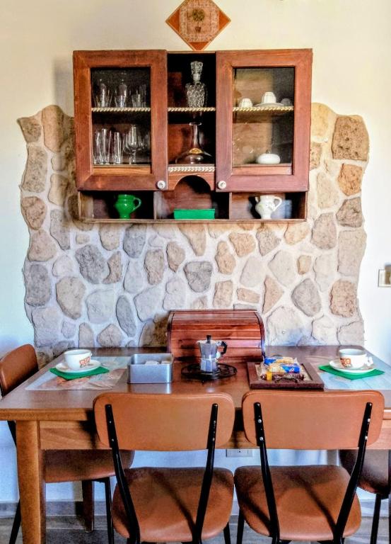 a dining room table with chairs and a stone wall at La Casa di Anna'80 in SantʼArcangelo