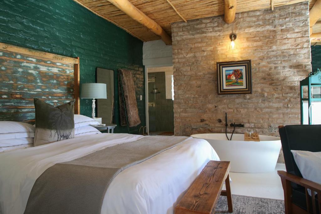 a bedroom with a large bed and a bath tub at Dennehof Karoo Guesthouse in Prince Albert
