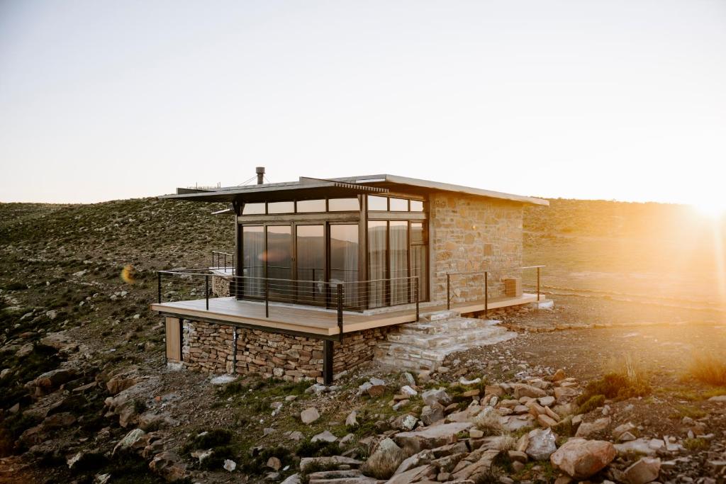 a house on top of a hill with the sun setting at Oudeberg Living- Oudeberg Lodge in Sutherland