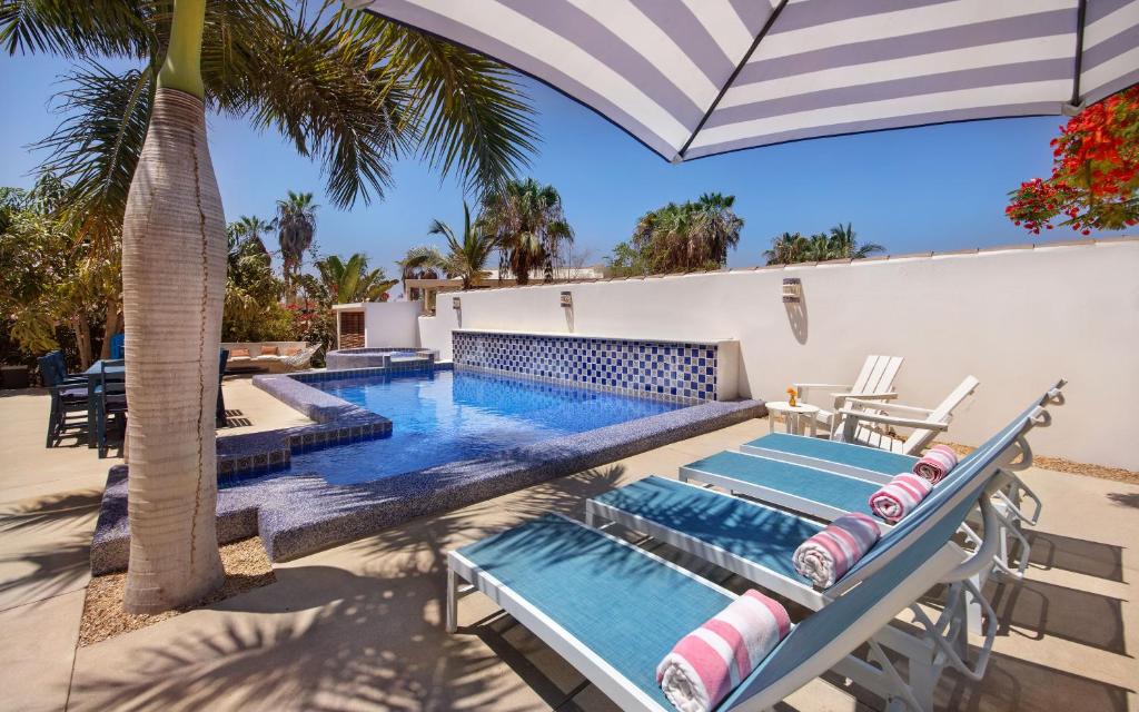 a pool with chairs and an umbrella on a patio at Casa Perla de Todos Santos in Todos Santos