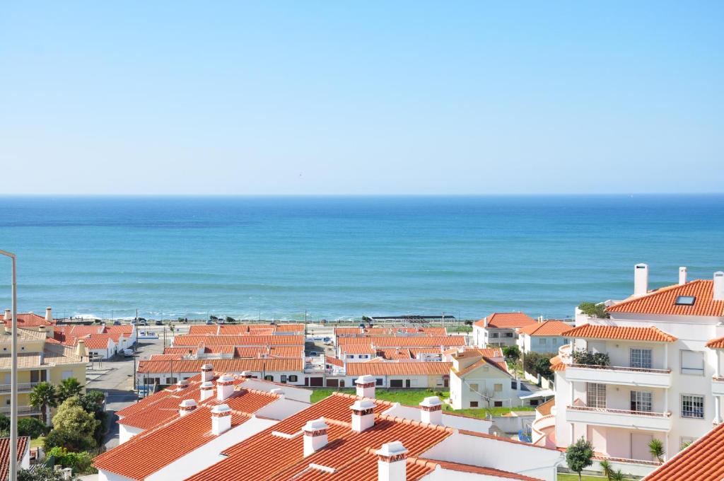 Ericeira Beach Place في إيريسييرا: إطلالة على مدينة ذات سطوح برتقالية وعلى المحيط