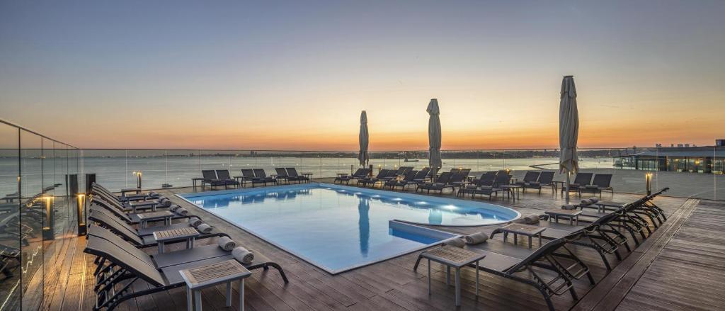 a swimming pool with chairs and a sunset in the background at DoubleTree By Hilton Istanbul - Moda in Istanbul