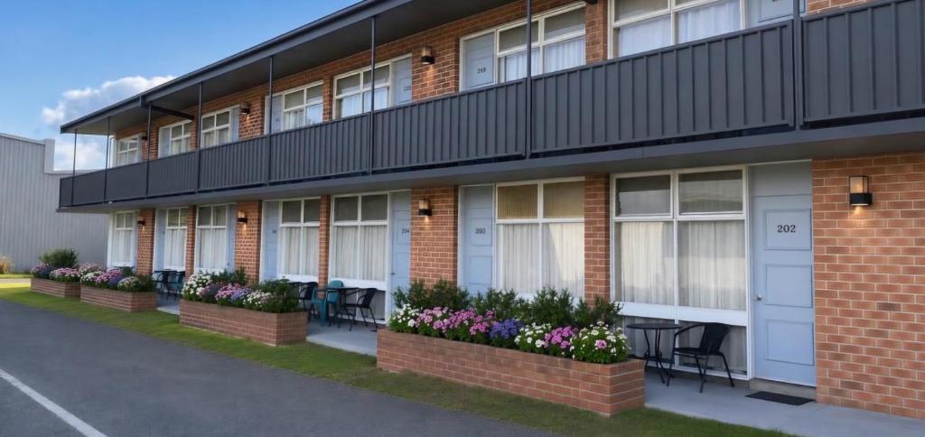 a building with a row of windows and flowers at Peninsula Motor Inn in Tyabb