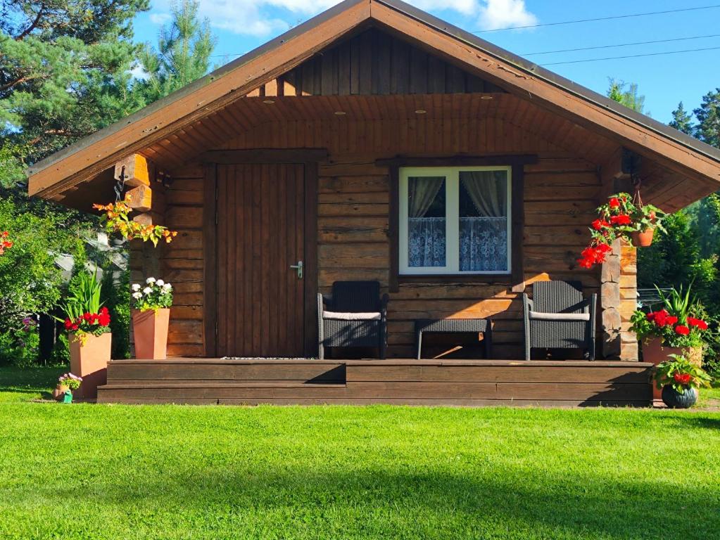 a log cabin with a porch and two chairs at Katase Guest House in Katase