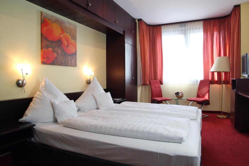 ヴュルツブルクにあるトップ ホテル アムバーガーのベッドルーム1室(白い大型ベッド1台付)