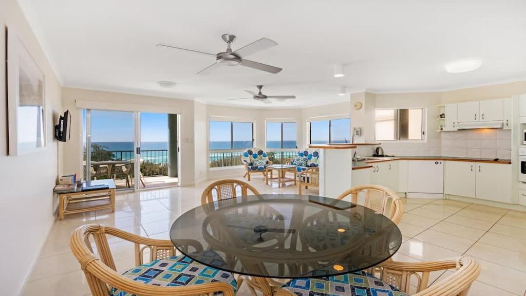 a kitchen and dining room with a glass table and chairs at Pacific Waves Apartments in Noosa Heads