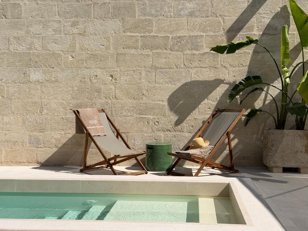 two lawn chairs sitting next to a swimming pool at Corte Dei Francesi in Maglie