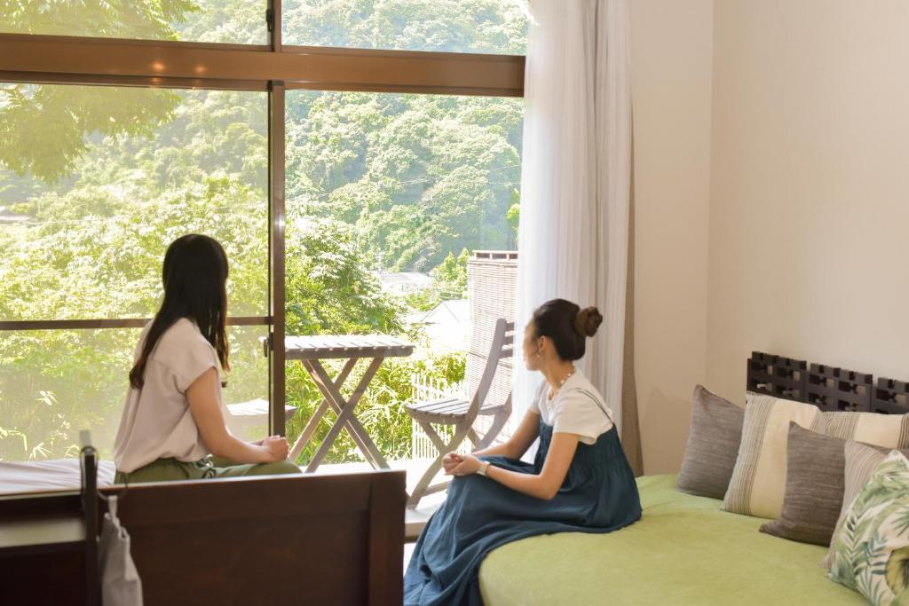 two women sitting on a couch looking out of a window at Kamakura Jomyoji Terrace-鎌倉浄明寺テラス- in Kamakura