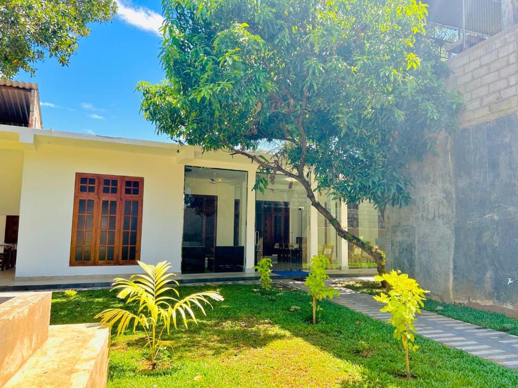a house with a tree in front of it at Blue Heaven Guest House Wellawaya in Wellawaya