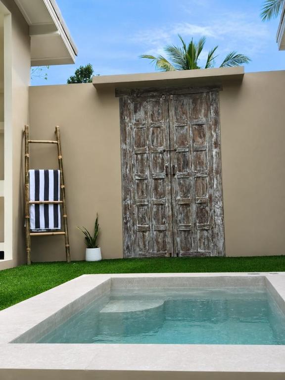 a pool in front of a house with a wooden door at La Caza Sowana in Ko Phangan