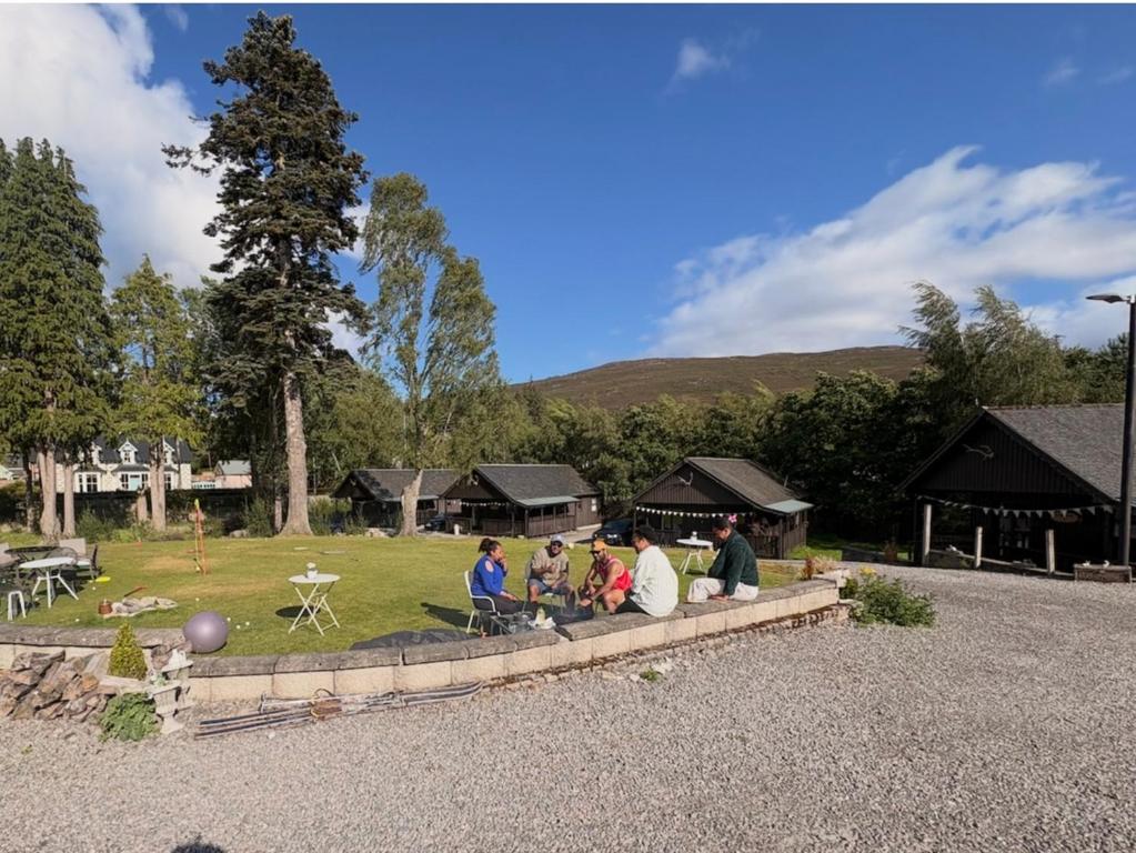 a group of people sitting on a ledge in a park at Braemar Lodge Cabins in Braemar