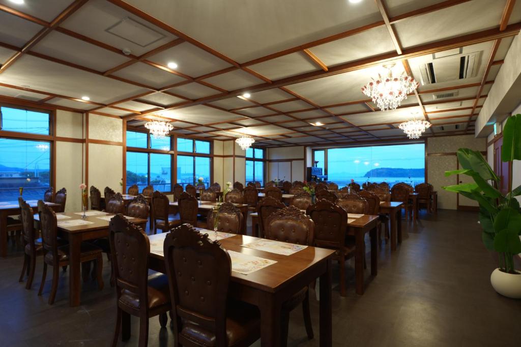 a dining room with tables and chairs and windows at フルールリゾート&ホテル in Nishio
