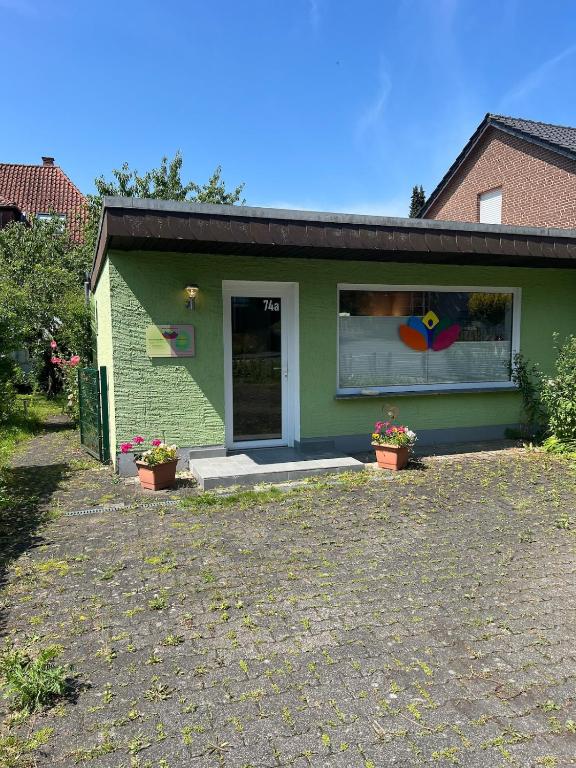 a green house with two flower pots in front of it at Kleines grünes Gästehaus in Altenbeken