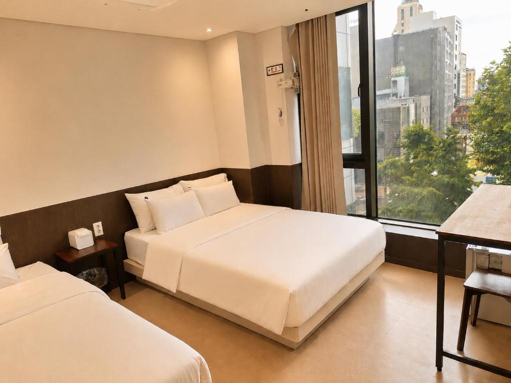 a hotel room with two beds and a window at Jongno The Stay Korea in Seoul