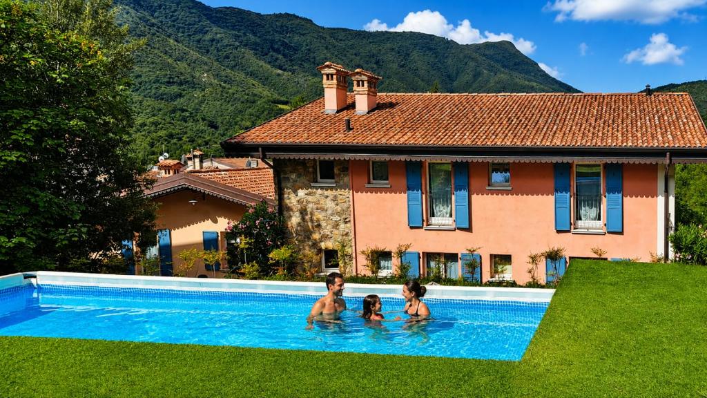 three people in a swimming pool in front of a house at Borgo alla Sorgente in Vallio Terme