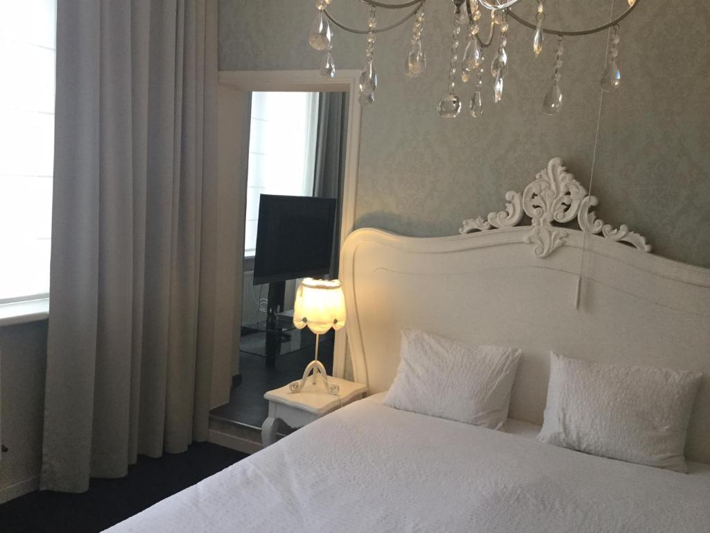 a bedroom with a white bed and a chandelier at B&B Wellness Yoake in Ypres