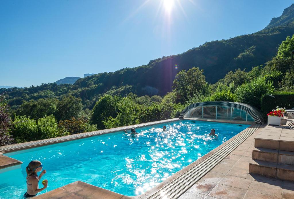 a swimming pool with mountains in the background at chalets studio du vieux frêne in Saint-Hilaire