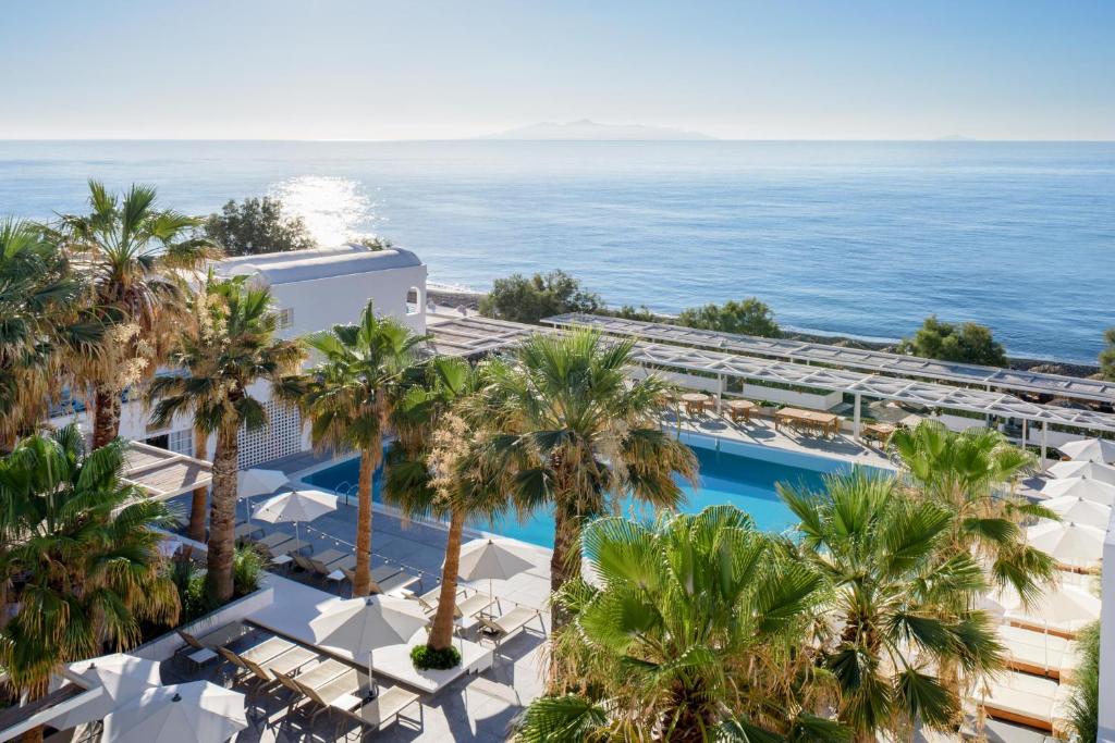 an aerial view of a resort with palm trees and the ocean at Kamari Beach Hotel in Kamari