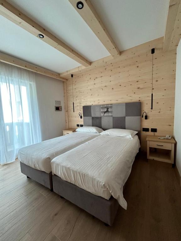 a bedroom with a large bed and a wooden wall at Garnì La Zondra in Canazei