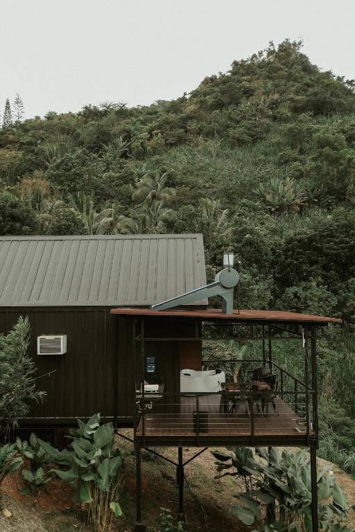 a house with a deck in front of a mountain at Grey Rock Mountain Cabin w/ Jacuzzi in Balamban