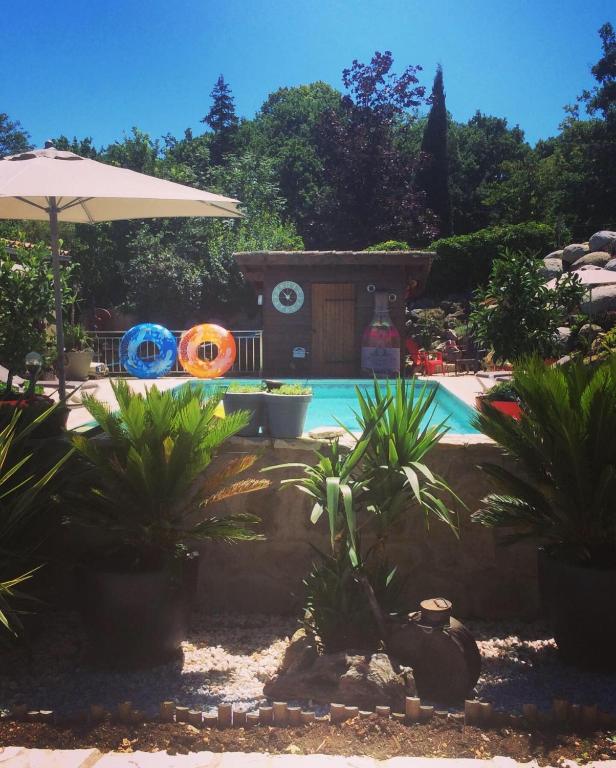 a swimming pool with plants and an umbrella at Au Barthas in Caylus