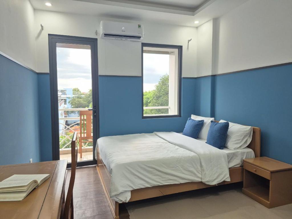 a blue bedroom with a bed and a window at Hyper house hotel in Buôn Ðũng