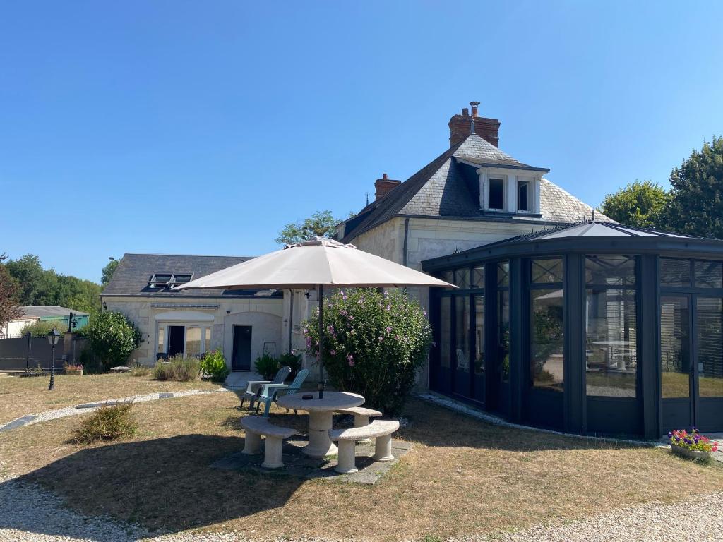 a picnic table and an umbrella in front of a house at Les Mariniers Chambres d'Hôtes avec aire de jeux proche du ZooParc de Beauval - Spa nordique en option in Mareuil-sur-Cher