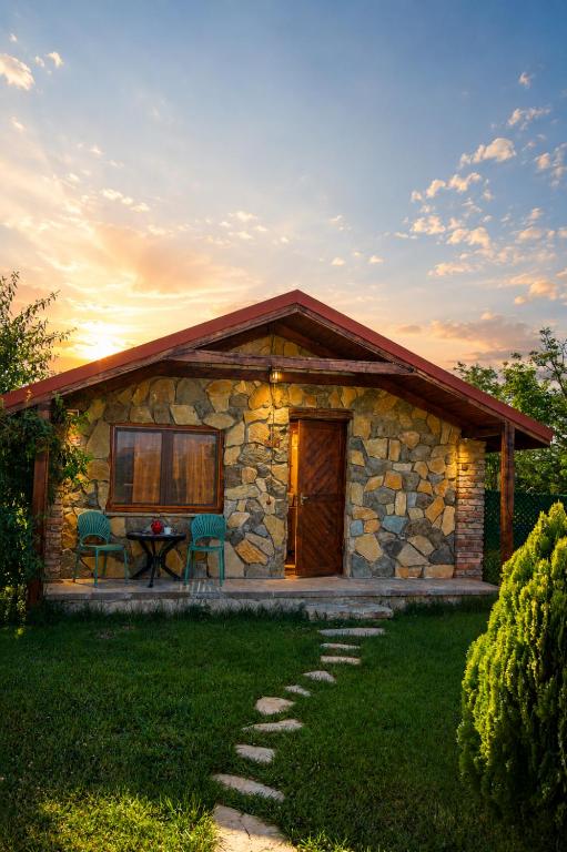 a stone house with a table and chairs in a yard at savane mukhranshi in Mukhrani
