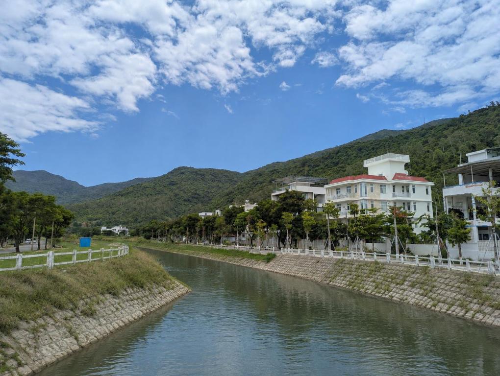 a river with buildings and trees next to a mountain at AN Apartment in Danang