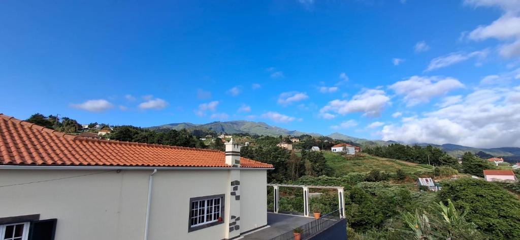a white building with a red roof with mountains in the background at A Casa de Santana in Santana