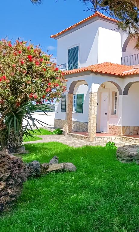 a white house with red flowers in the yard at Great for Families in Lourinhã-Double Rooms-Private Baths-Free Parking & Extra Bed in Lourinhã