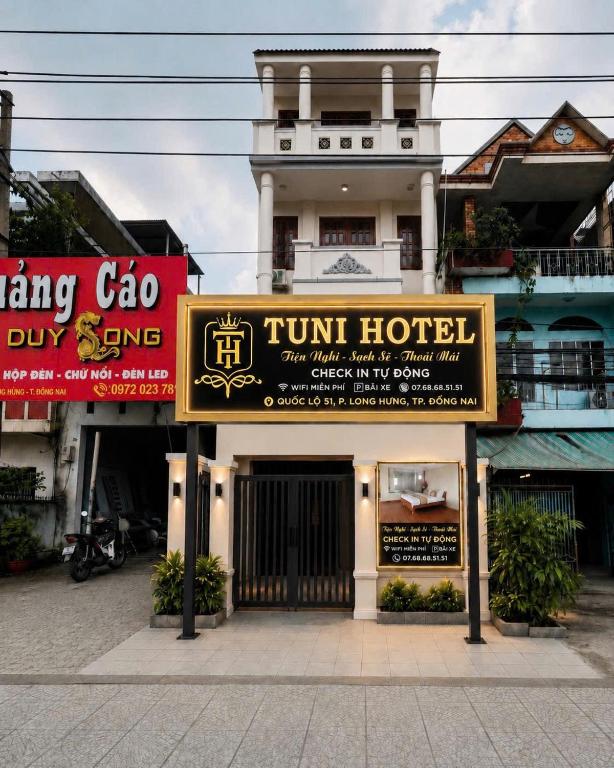 a hotel with signs in front of a building at TUNI Hotel in Long Bình