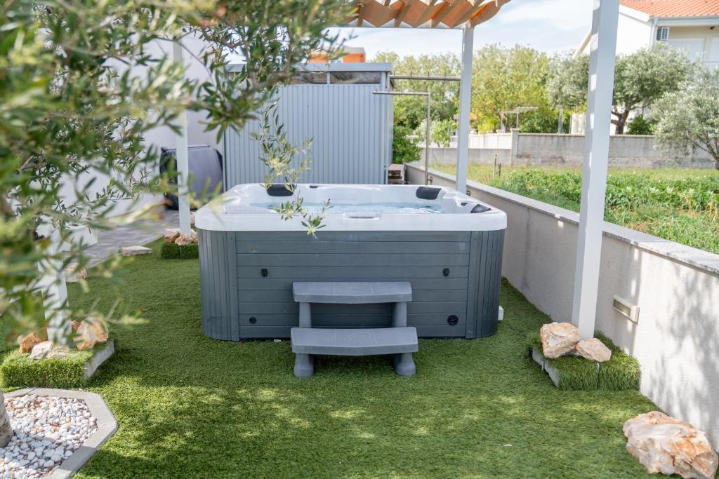 a hot tub in a yard with a bench at Beachfront Reiterer Villa V3 with Jacuzzi 30 meters from the Beach - CROWONDER LUXURY RENT in Privlaka